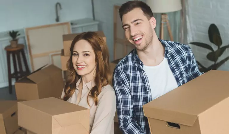 happy couple with boxes inside of a house