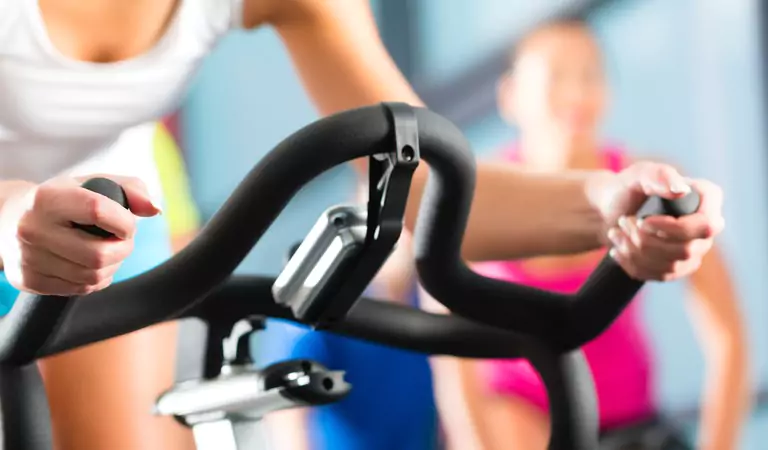 cropped picture of women doing cycling at gym