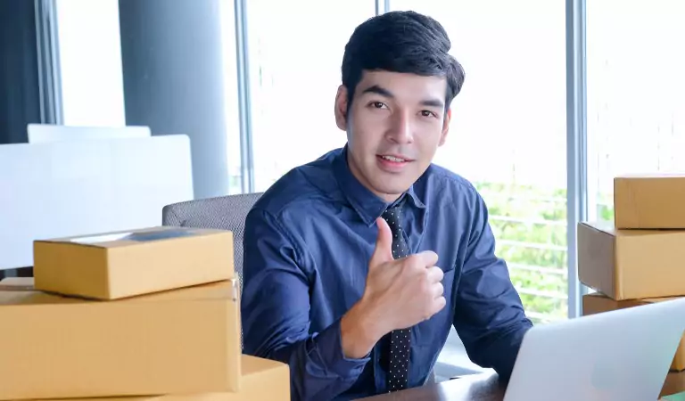 young man showing thumbs up and working on a laptop