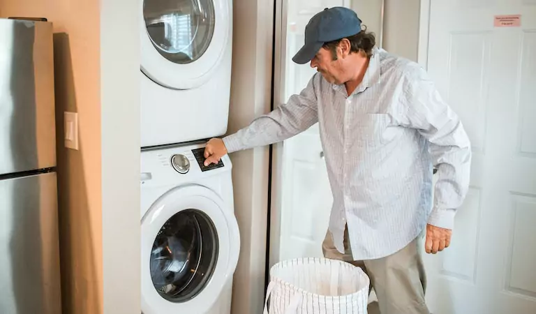 man operating a washer and washing cloths