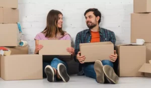 couple sitting on the floor with some cardboard boxes