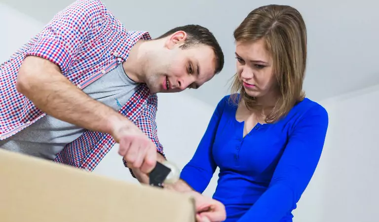 couple trying to pack a cardboard box