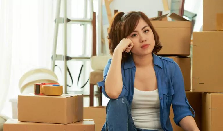 woman looking worried and sitting with some cardboard boxes